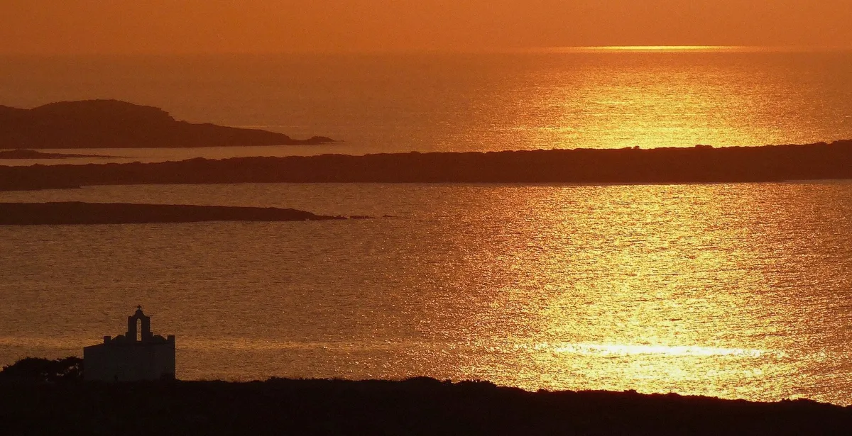 Golden sunset over Paros seen from the water on a two-hour evening cruise