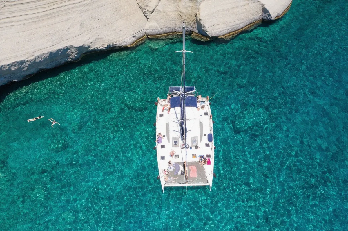 Sailing catamaran at anchor in a turquoise Cycladic bay